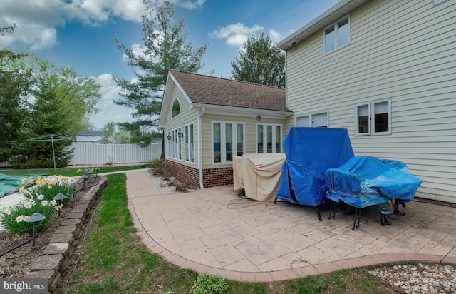 rear view of property with fence, a patio area, and roof with shingles
