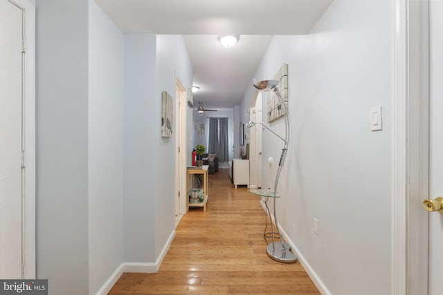 hall with light wood-style flooring and baseboards
