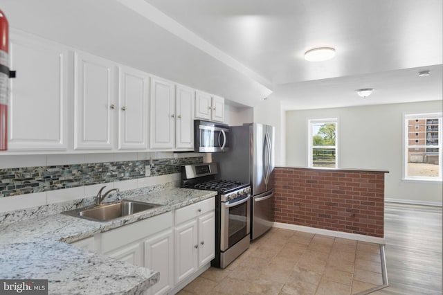 kitchen with stainless steel appliances, a sink, white cabinetry, and baseboards