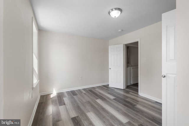 unfurnished bedroom with wood finished floors, baseboards, and washing machine and clothes dryer