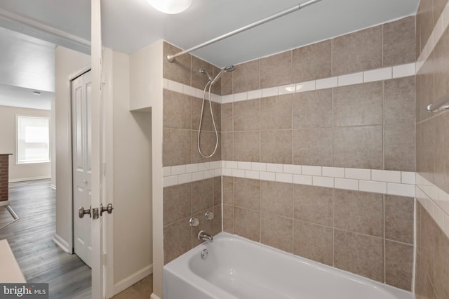 full bath featuring bathing tub / shower combination, baseboards, and wood finished floors