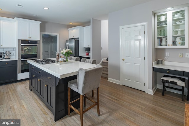 173 Christopher Dr, Princeton, NJ 08540 - kitchen featuring double wall oven, freestanding refrigerator, white cabinetry, a breakfast bar area, and light wood-style flooring