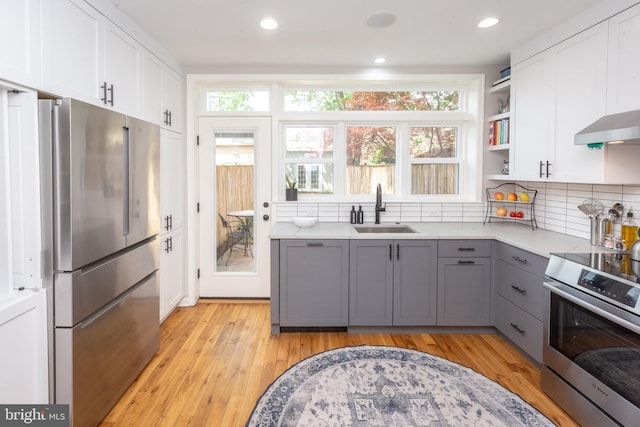 kitchen with gray cabinets, appliances with stainless steel finishes, open shelves, a sink, and white cabinets