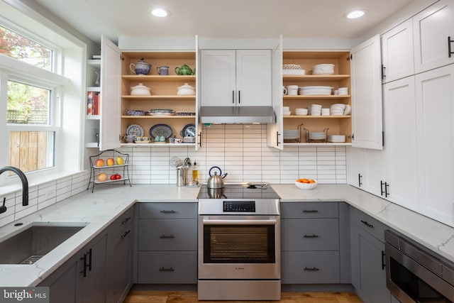 kitchen featuring open shelves, gray cabinets, appliances with stainless steel finishes, and under cabinet range hood