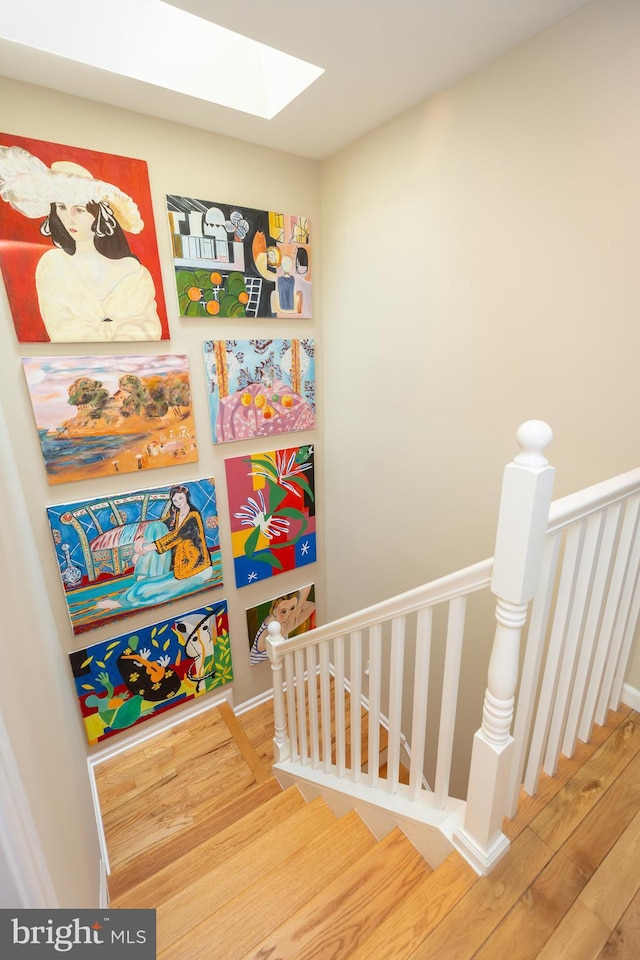 stairs with a skylight and wood finished floors