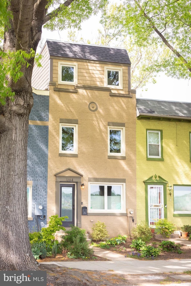 view of front of house featuring a shingled roof and brick siding