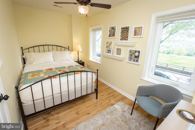 bedroom featuring baseboards, a ceiling fan, wood finished floors, and visible vents