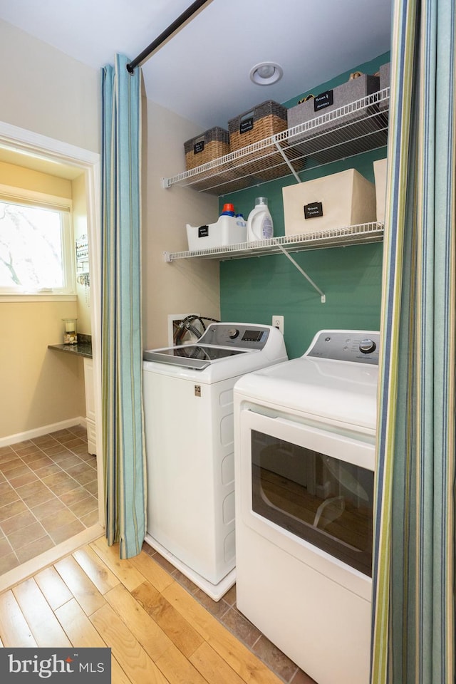 washroom featuring laundry area, baseboards, independent washer and dryer, and wood finished floors