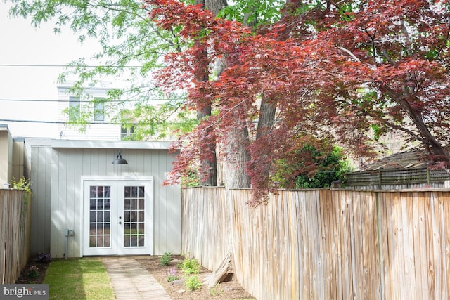 view of outbuilding featuring fence and french doors