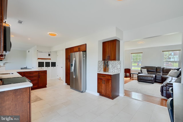 kitchen featuring visible vents, open floor plan, stainless steel fridge, light countertops, and a sink