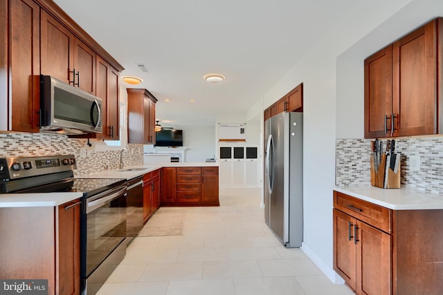 kitchen featuring a sink, decorative backsplash, a peninsula, and stainless steel appliances