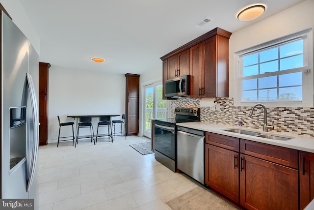 kitchen featuring a sink, decorative backsplash, appliances with stainless steel finishes, and light countertops