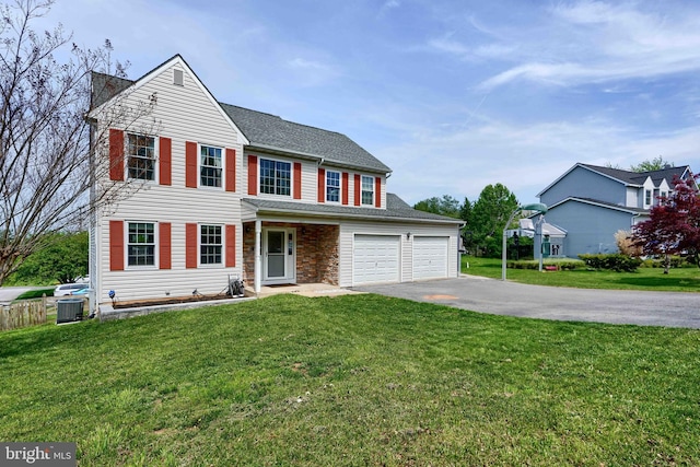 traditional home featuring a garage, central air condition unit, a front lawn, and aphalt driveway