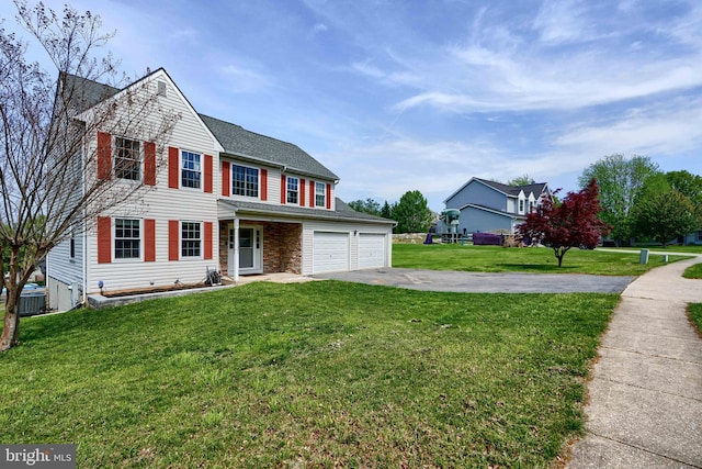 traditional-style house featuring a front lawn, aphalt driveway, a garage, cooling unit, and covered porch