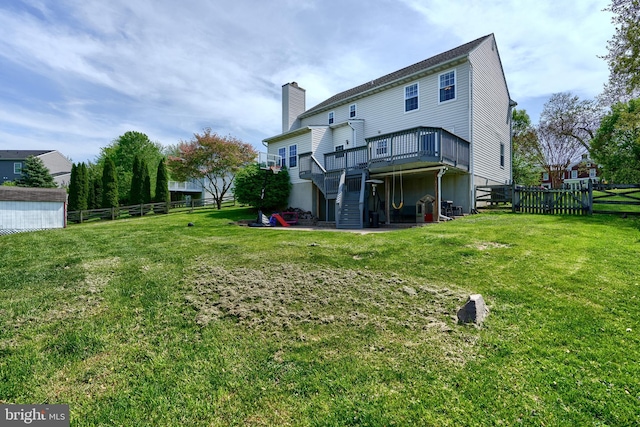 rear view of property with fence, a wooden deck, stairway, a chimney, and a lawn