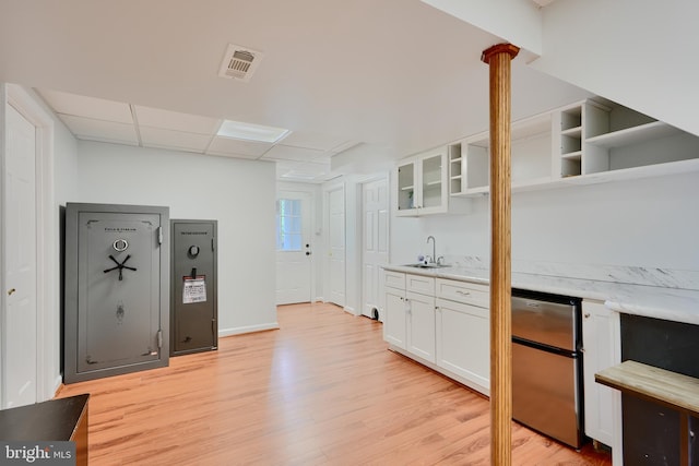 kitchen featuring fridge, open shelves, a sink, light wood-style floors, and white cabinetry