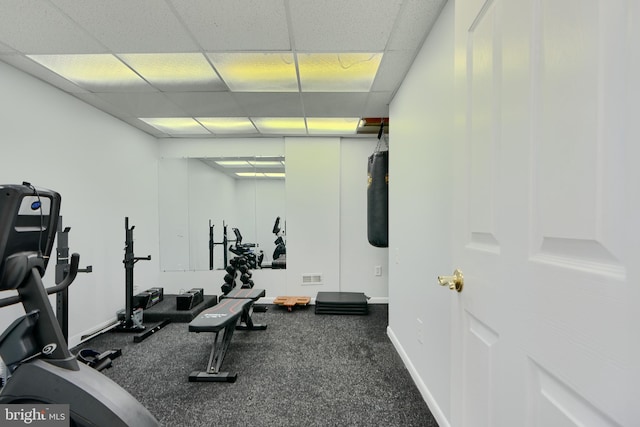 exercise room with visible vents, a paneled ceiling, and baseboards