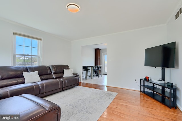 living area featuring light wood-type flooring, ornamental molding, and baseboards