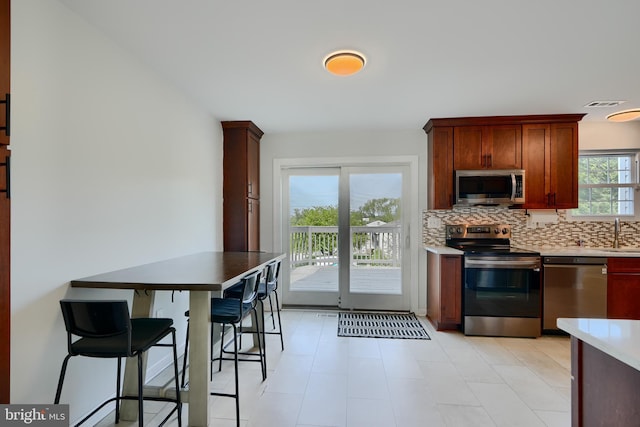 kitchen featuring appliances with stainless steel finishes, a sink, light countertops, backsplash, and visible vents