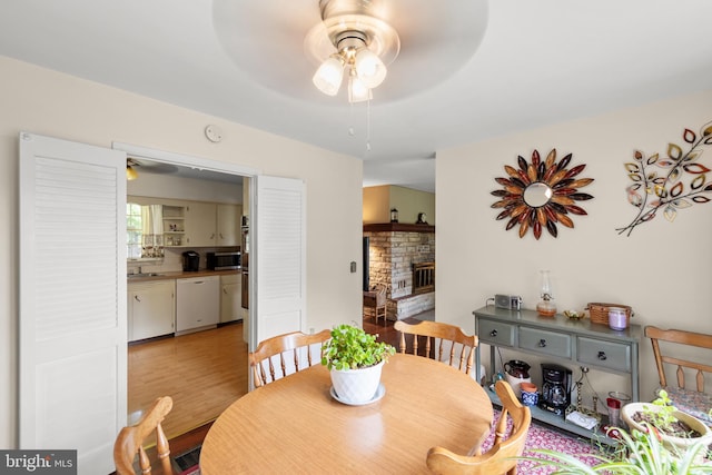2385 Heide Cooper Rd, Shanks, WV 26761 - dining space with ceiling fan, a stone fireplace, and light wood-style flooring