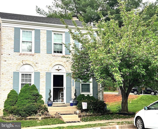 view of front of property featuring a chimney and brick siding