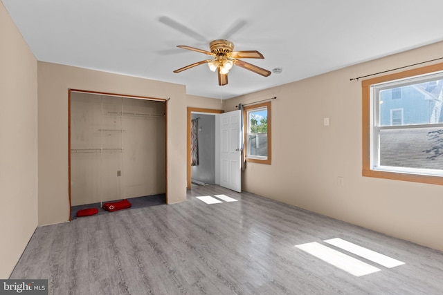 unfurnished bedroom featuring a ceiling fan, a closet, and wood finished floors