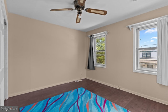 unfurnished bedroom with visible vents, dark wood-style flooring, ceiling fan, and baseboards