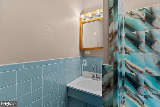 bathroom with vanity, wainscoting, and tile walls