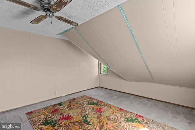 bonus room featuring a textured ceiling, ceiling fan, vaulted ceiling, and light carpet