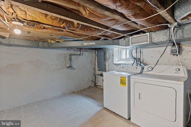 clothes washing area featuring electric panel, visible vents, laundry area, and washer and clothes dryer