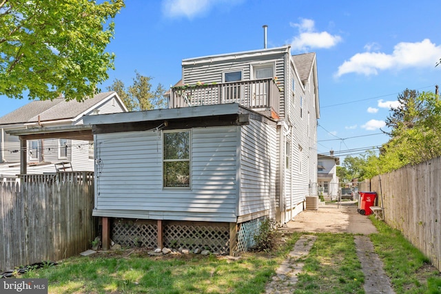 rear view of house with a fenced backyard and a balcony