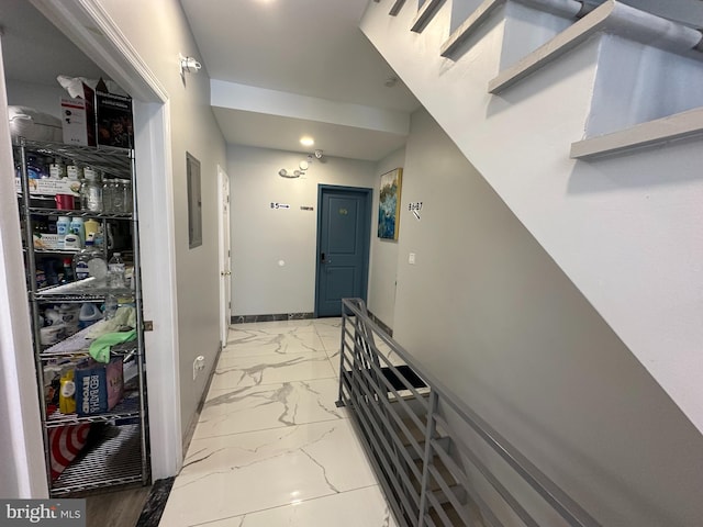 hallway with recessed lighting, marble finish floor, electric panel, and baseboards