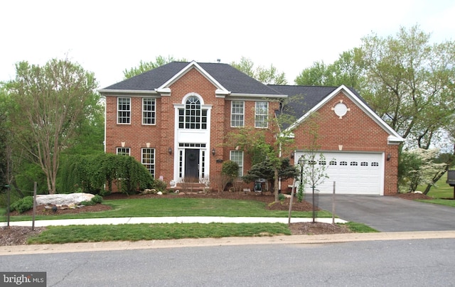 colonial-style house featuring a garage, brick siding, aphalt driveway, and a front yard