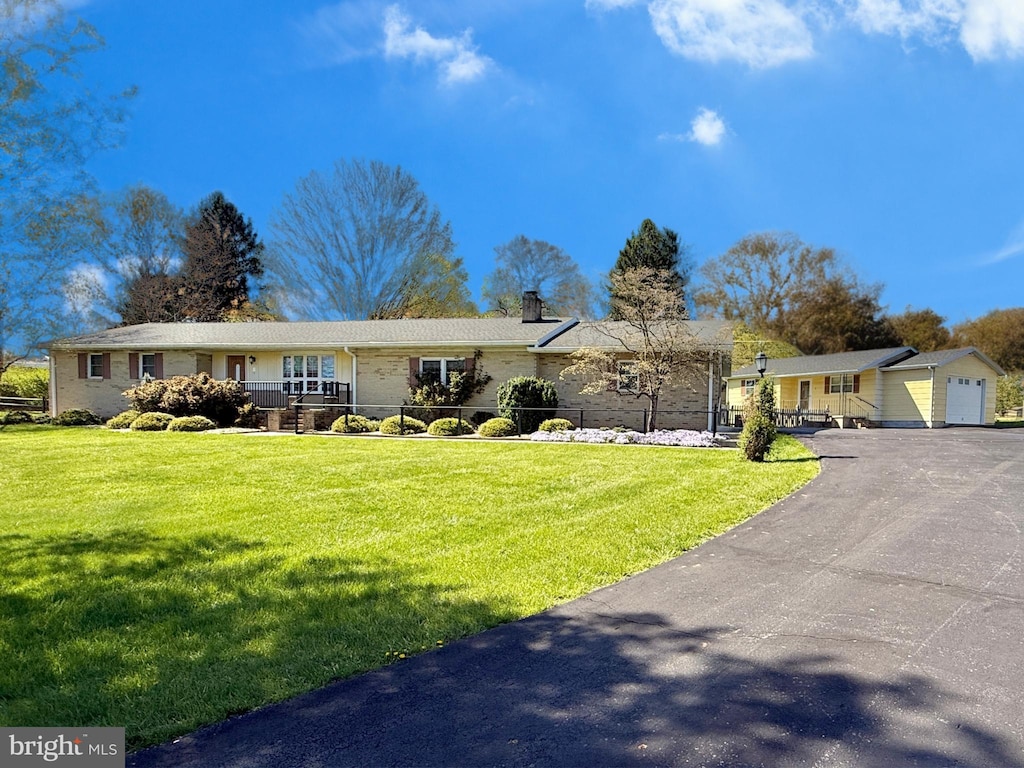 single story home featuring a chimney, a front yard, and aphalt driveway