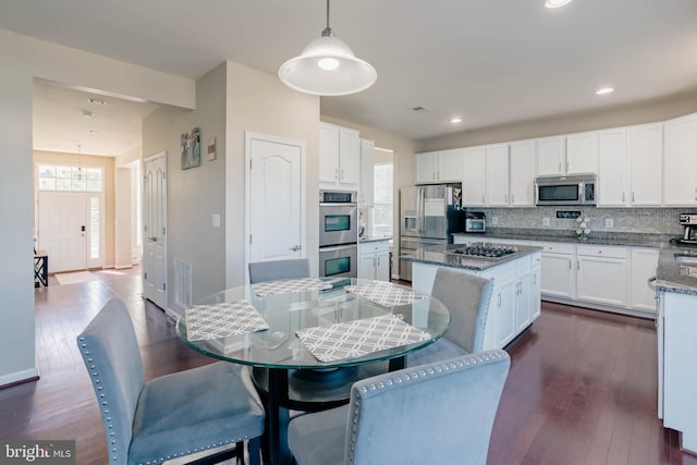 kitchen with dark wood finished floors, appliances with stainless steel finishes, white cabinets, and tasteful backsplash