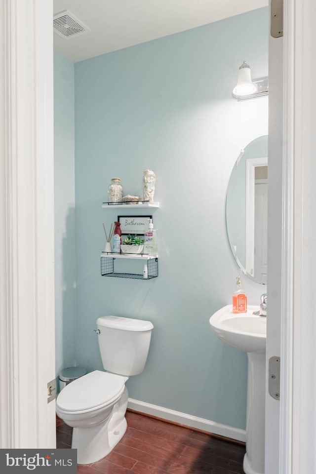 half bathroom featuring visible vents, baseboards, wood finished floors, and toilet