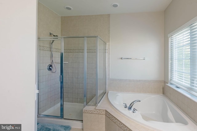 full bath featuring a garden tub, a healthy amount of sunlight, and a shower stall