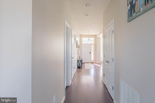 hall with visible vents, baseboards, and wood finished floors