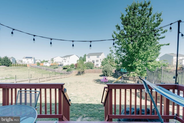 view of yard with a fenced backyard, a trampoline, a playground, and a residential view