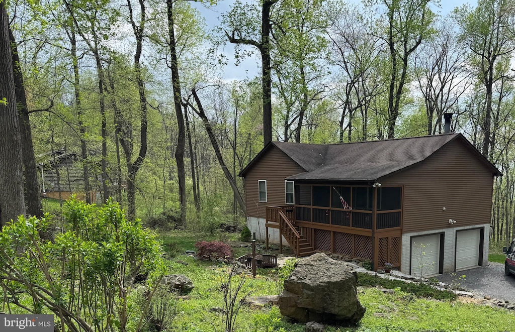 view of front of home featuring stairway, a shingled roof, driveway, a deck, and an attached garage