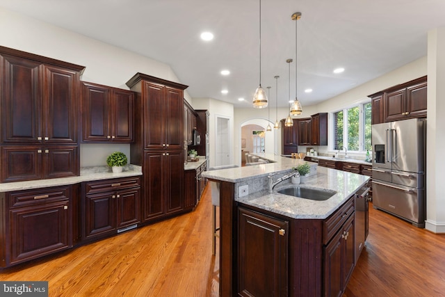 2619 Sledding Hill Rd, Oakton, VA 22124 - kitchen featuring a center island with sink, light wood-type flooring, arched walkways, a sink, and appliances with stainless steel finishes