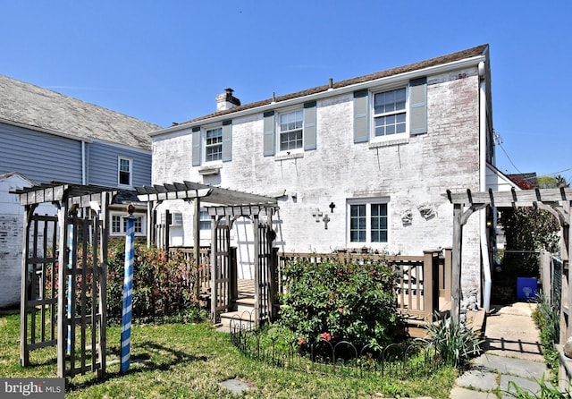 rear view of property featuring a pergola, fence, and a chimney