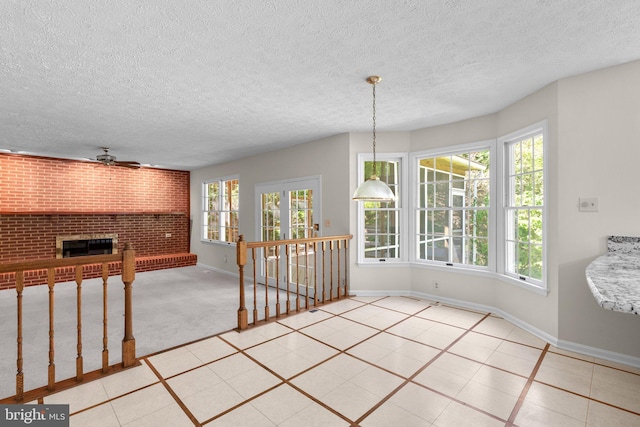 dining area featuring baseboards, ceiling fan, a brick fireplace, and a textured ceiling