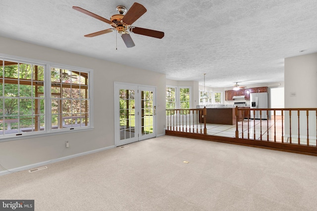 spare room featuring ceiling fan, a textured ceiling, light colored carpet, visible vents, and baseboards