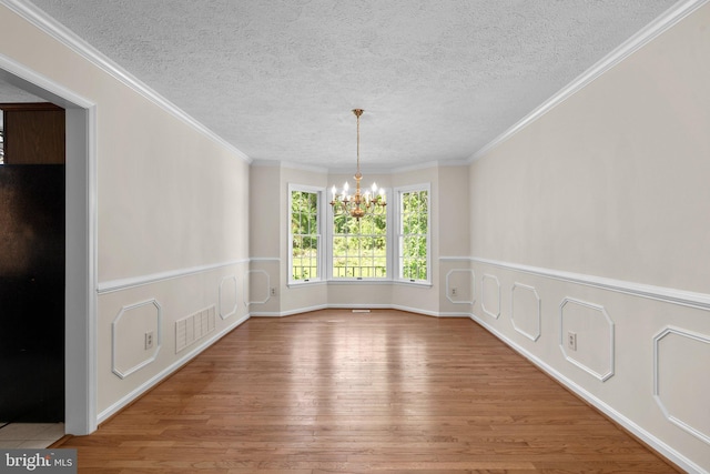 unfurnished dining area featuring a textured ceiling, a notable chandelier, wood finished floors, and visible vents