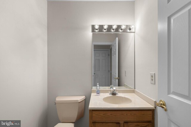 half bath featuring vanity and toilet