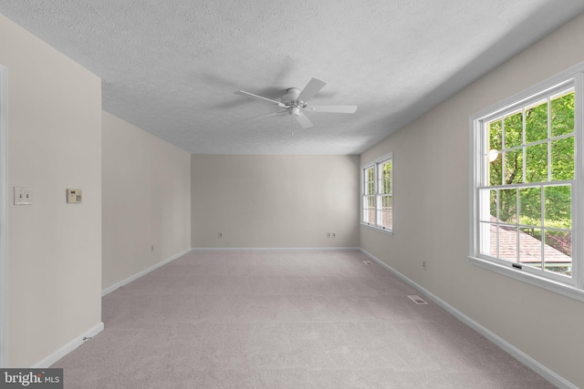 unfurnished room with baseboards, a textured ceiling, ceiling fan, and light carpet