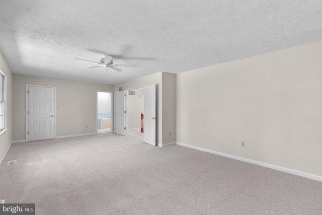 unfurnished room with baseboards, a textured ceiling, ceiling fan, and light carpet