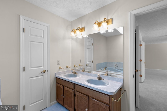 bathroom with baseboards, double vanity, a textured ceiling, and a sink