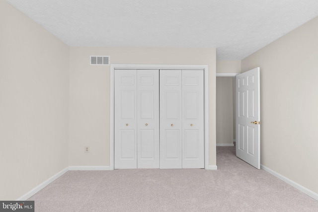 unfurnished bedroom with carpet floors, baseboards, a closet, and visible vents
